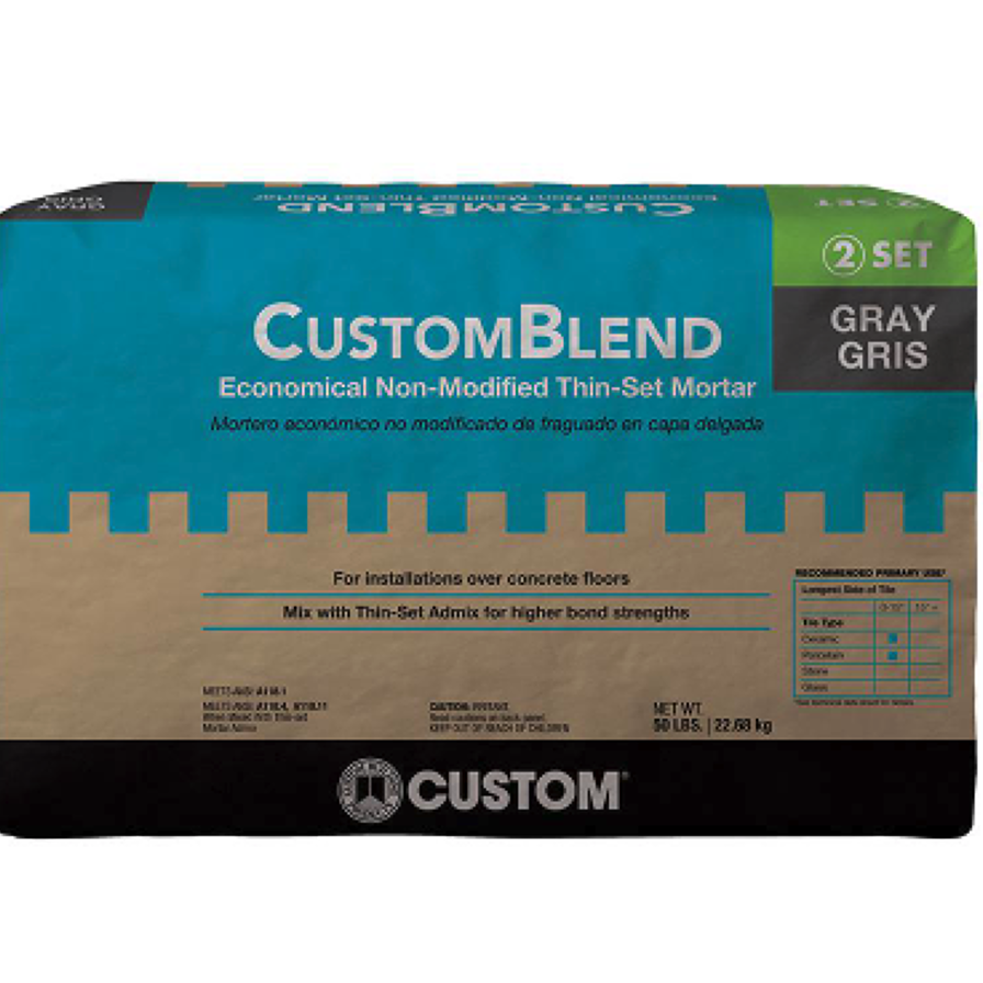 A 50 lb. bag of Go Build 50 lb. Non-Modified Thinset Mortar - Gray, for concrete floors, comes in blue, black, and beige packaging with ANSI A118.1 rating and mixing instructions from The Fastest Way To Build brand.