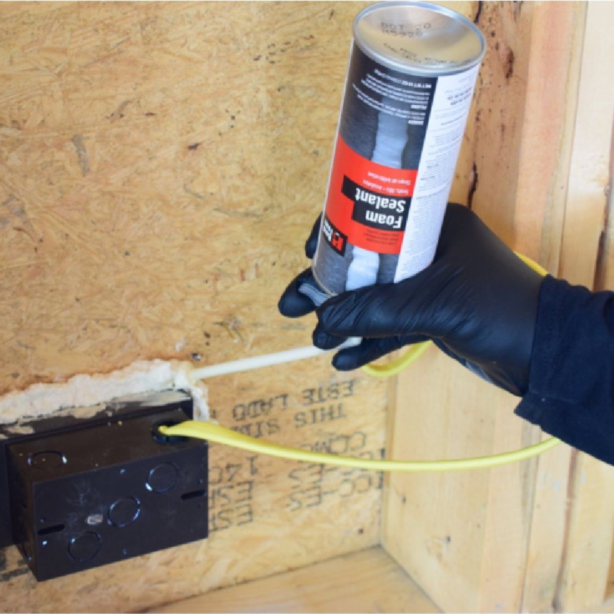 A gloved individual uses a dispensing unit to apply HANDIFOAM P30002 12oz Low Pressure Foam Sealant OCF to a hole in wood, emphasizing its role as an air infiltration barrier and moisture-cured polyurethane foam sealant.