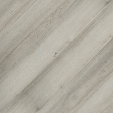Light gray MSI Cyrus Brianka Luxury Vinyl Planks (23.77 SQFT/box) feature subtle grains and knots, laid diagonally with a CrystaLux™ wear layer for a smooth, matte, silvery gray wood look on this rigid-core vinyl surface.