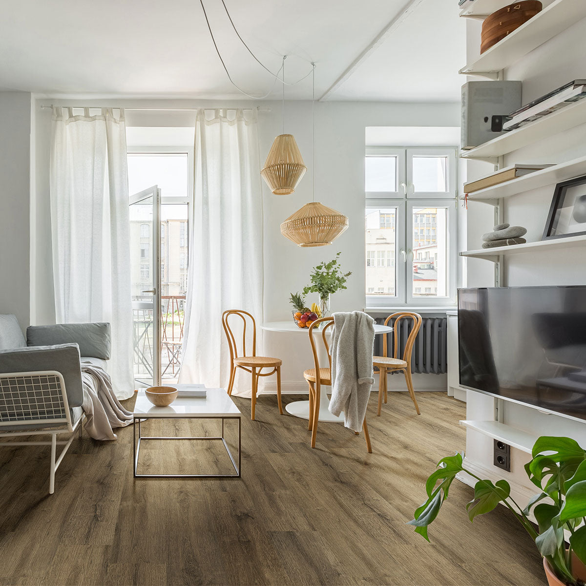 Bright, modern living and dining area with MSI Cyrus Walnut Waves Luxury Vinyl Planks (23.77 sq ft), white walls, sofa, glass coffee table, round dining table with chairs, hanging lamps, large windows with sheer curtains, and wall-mounted TV shelf.