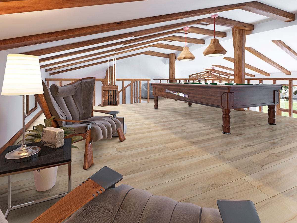 A spacious attic room with wooden beams, a pool table, two modern gray armchairs, a side table with a lamp, and pendant lights, all set on MSI XL Cyrus Akadia Luxury Vinyl Planks flooring.