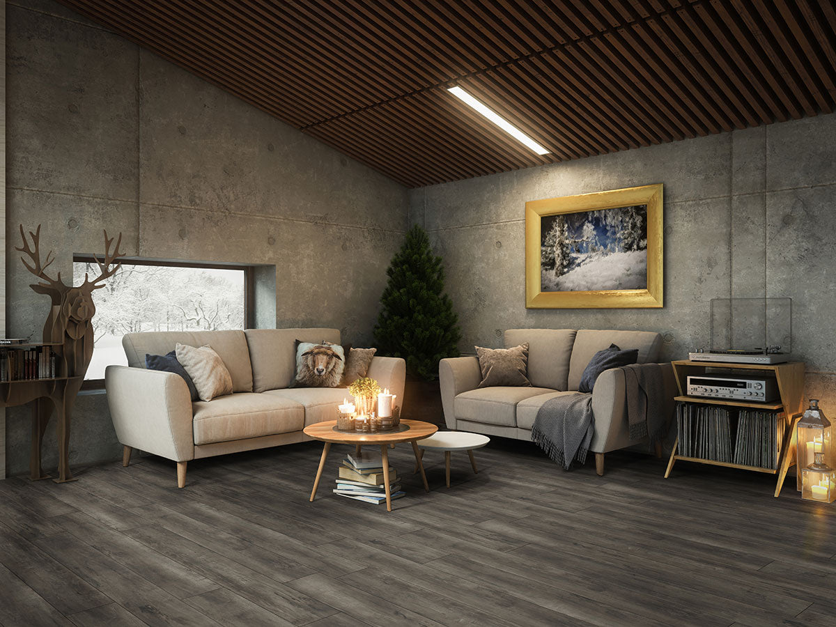 Cozy living room with beige sofas, a round coffee table with candles, indoor tree, and snowy landscape painting. Warm lighting and MSI XL Cyrus Billingham Luxury Vinyl Planks flooring add charm and wood accents enhance the relaxed feel.