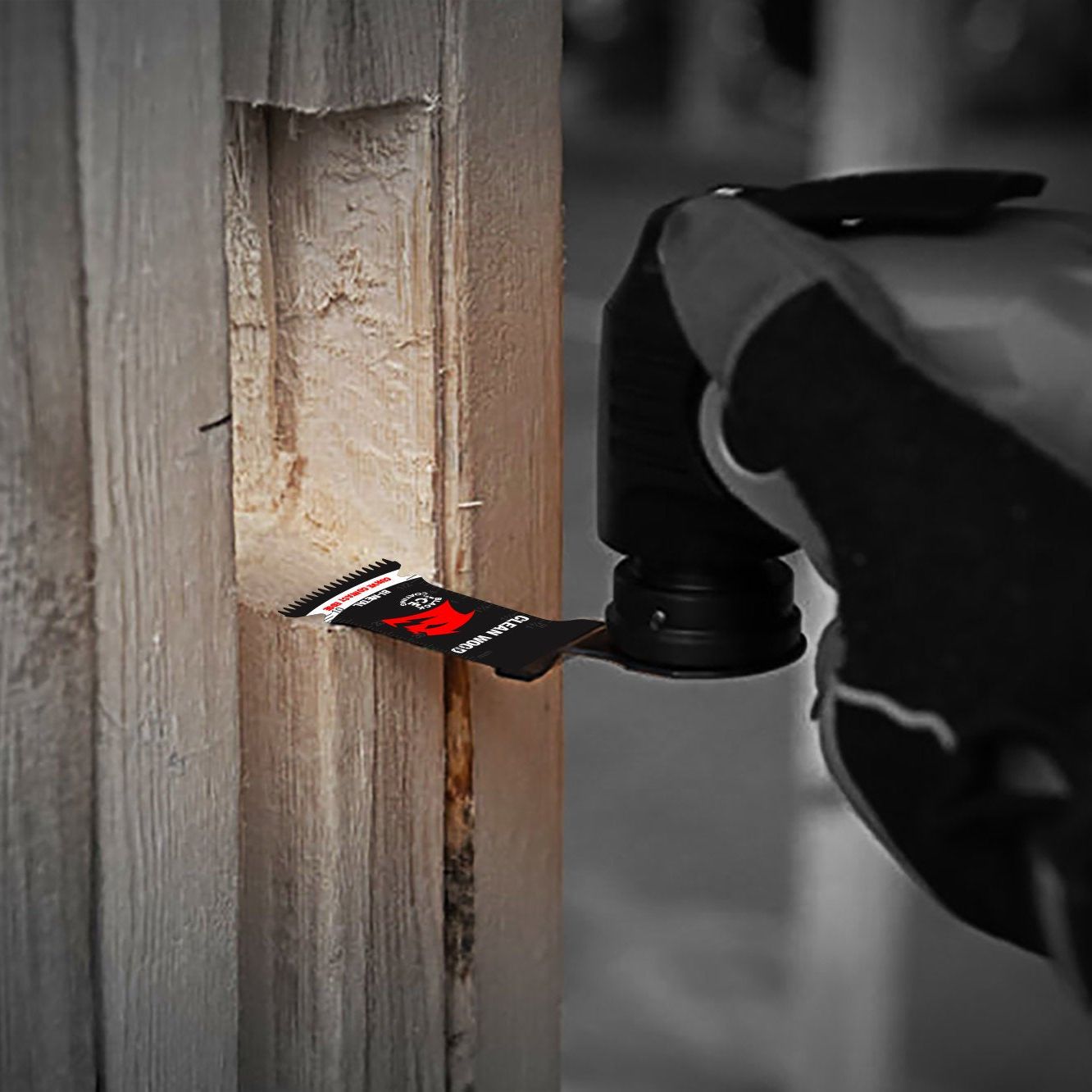 A hand wearing a work glove uses a Diablo DIABLO DOS125JBW3 Demo Demon™ Starlock Bi-Metal Oscillating Blade with a red and silver ultra-hardened cutting edge to precisely slice wood, standing out against the blurred grayscale background.