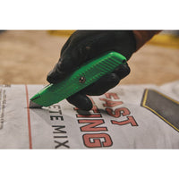 A gloved hand uses the STANLEY® Hi-Visibility Retractable Knife to cut open a white FAST SETTING CONCRETE MIX bag.