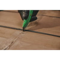 A gloved hand uses the STANLEY® Hi-Visibility Retractable Knife to cut brown cardboard packaging secured with a black plastic strap.