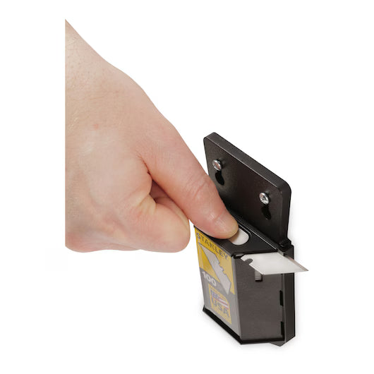 A hand pulls a STANLEY 11-921A Heavy-Duty Utility Blade from a black wall-mounted dispenser holding a 100-pack of replacement blades by STANLEY.