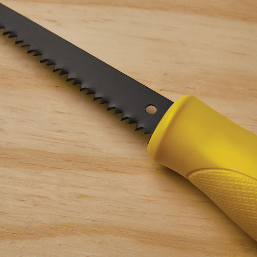 A close-up of the STANLEY® Jab Saw, 6TPI features a black jagged blade and yellow handle, resting on a light wooden surface—a versatile woodworking tool from STANLEY.