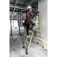 A construction worker in a helmet and tool belt stands on a LITTLE GIANT 15398-001 MightyLite IA 8 ft. 300 lb. fiberglass stepladder inside a building with exposed beams and unfinished walls.
