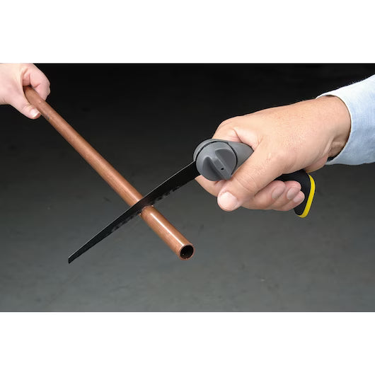 One person uses a STANLEY 3-in-1 Multi-Purpose Saw to cut a copper pipe while another holds it steady, all set against a plain, dark background.