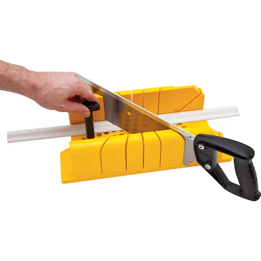 A person uses the STANLEY® Clamping Mitre Box with Saw by STANLEY to cut a white trim piece, holding it steady with one hand and sawing with the other.