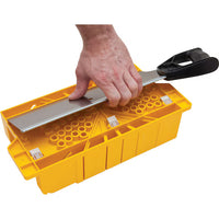 A hand uses a black-handled saw to cut over a yellow STANLEY® Clamping Mitre Box with circular holes, by STANLEY.