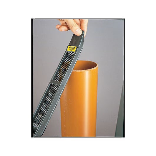 A hand holds a STANLEY® SURFORM FLAT FILE - REGULAR CUT 10IN - 250MM above the edge of an upright orange plastic pipe, preparing to smooth or file the pipe’s rim.