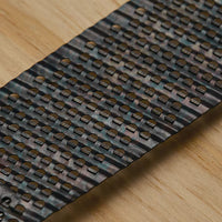 A close-up of the STANLEY 5-1/2 IN SURFORM® POCKET FINE CUT REPLACEMENT BLADE shows its textured, patterned metal segments on a light wood surface, highlighting its design and use as a precision woodworking tool.