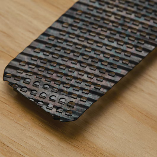 A close-up of the STANLEY 5-1/2 IN SURFORM® POCKET FINE CUT REPLACEMENT BLADE with sharp, patterned teeth on wood, displaying its textured design—an essential upgrade for any woodworking tool kit.