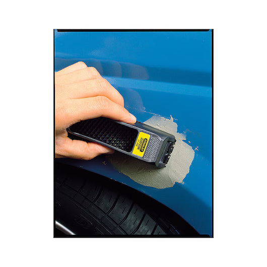 A hand uses the STANLEY 6 IN SURFORM® POCKET PLANE to smooth filler on a blue car’s body above the wheel.