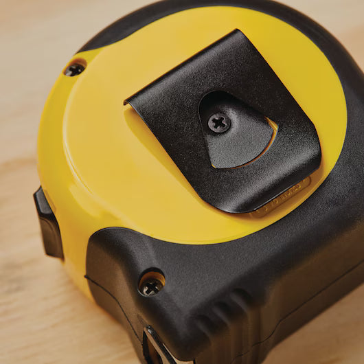A close-up of the STANLEY 25 ft FATMAX Classic Tape Measure, featuring a yellow and black design with a metal belt clip, resting on light wood. This durable tool from STANLEY ensures precise measurements for any project.