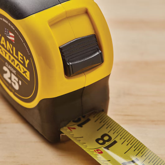 Close-up of the 25 ft STANLEY® FATMAX® Classic Tape Measure, with its yellow and black finish, extended over a wooden surface.