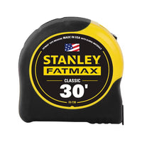 The 30 ft STANLEY® FATMAX® Classic Tape Measure features a yellow and black casing with the STANLEY logo, “Made in USA” text, an American flag on the label, and BladeArmor® coating for enhanced durability.
