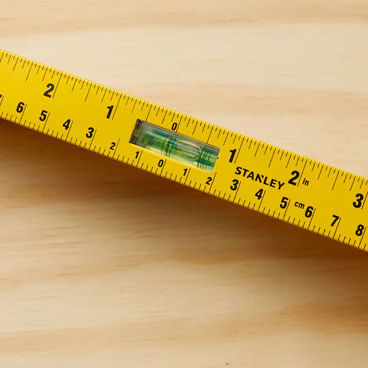 A STANLEY 48 in I-Beam 180 Level, ideal for construction projects, is placed diagonally on a light wooden surface.