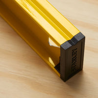 A close-up of a yellow STANLEY 48 in I-Beam 180 Level with a black end cap on light wood—a professional-grade tool ideal for construction projects.