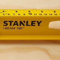 A close-up of the STANLEY 48 in I-Beam 180 Level, featuring a built-in inch ruler, placed on a light wooden surface—perfect for precise measurements in construction projects.