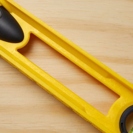 A close-up of the STANLEY 24 in High-Impact ABS Level, featuring a rectangular cutout and black end components, resting on a light wooden surface.