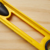 A close-up of the STANLEY 24 in High-Impact ABS Level, featuring a rectangular cutout and black end components, resting on a light wooden surface.