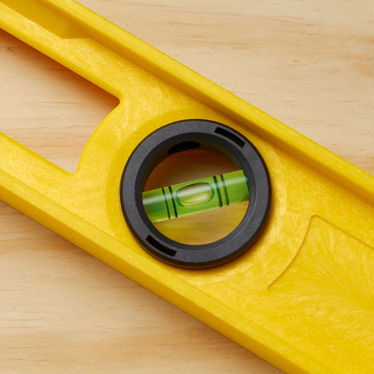 A close-up of the STANLEY 24 in High-Impact ABS Level on a light wooden surface, showing its centered bubble vial and highlighting this reliable leveling tool in a perfectly level position.
