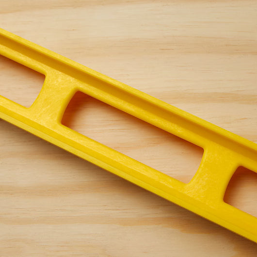 A close-up of the STANLEY® ABS I-Beam Level 1200mm by Go Build, The Fastest Way To Build, placed diagonally on a light wooden surface.