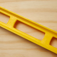 A close-up of the STANLEY® ABS I-Beam Level 1200mm by Go Build, The Fastest Way To Build, placed diagonally on a light wooden surface.