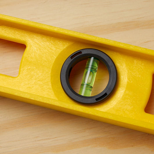 A close-up of the STANLEY® ABS I-Beam Level 1200mm by Go Build, The Fastest Way To Build, on a wooden surface with the bubble centered—an accurate and reliable leveling tool for precise measurements.