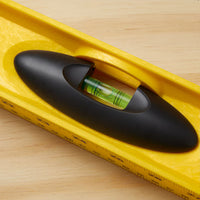 A close-up of the STANLEY® ABS I-Beam Level 1200mm by Go Build, The Fastest Way To Build, featuring its green liquid vial and black handle, placed on a wooden surface.