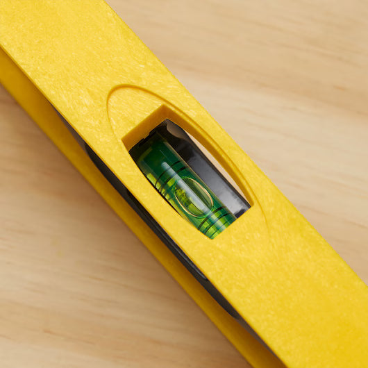 Close-up of the STANLEY® ABS I-Beam Level 1200mm by Go Build, The Fastest Way To Build, on wood. The centered bubble in the green vial shows this leveling tool is perfectly aligned.