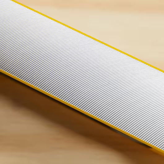 A close-up of the STANLEY® FATMAX® Aluminum Box Beam Level 1200mm shows its fine white diagonal ridges and yellow edges on a light wooden surface—a professional STANLEY tool built for precise leveling.