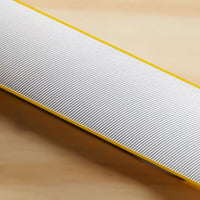 A close-up of the STANLEY® FATMAX® Aluminum Box Beam Level 1200mm shows its fine white diagonal ridges and yellow edges on a light wooden surface—a professional STANLEY tool built for precise leveling.