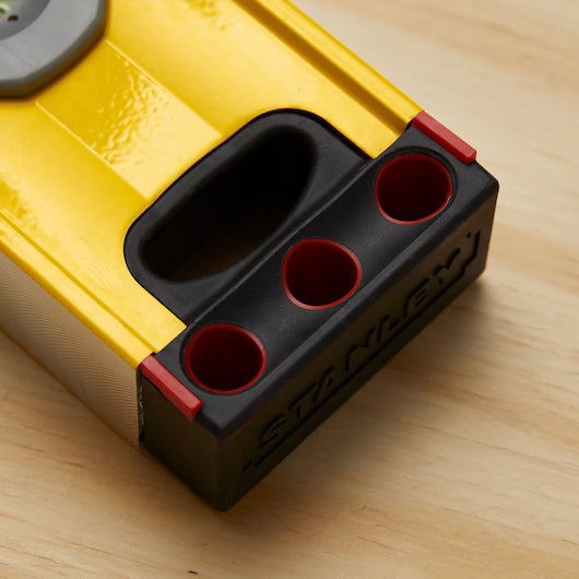 Close-up of a yellow and black STANLEY® FATMAX® Aluminum Box Beam Level 1200mm, featuring three round holes, lying on a light wooden surface.