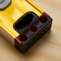 Close-up of a yellow and black STANLEY® FATMAX® Aluminum Box Beam Level 1200mm, featuring three round holes, lying on a light wooden surface.