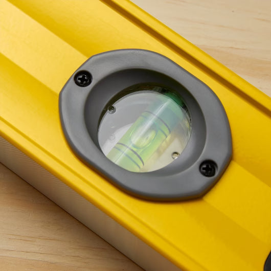 Close-up of the STANLEY® FATMAX® Aluminum Box Beam Level 1200mm on a light wooden surface, showing the centered bubble in its circular vial for precise leveling.