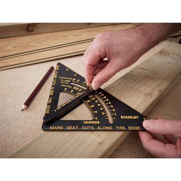 A user marks an angle on a wooden board with a STANLEY® ALUMINIUM QUICKSQUARE WITH ARM and pencil, showcasing accurate carpentry measuring and layout using STANLEY tools, with wood pieces and a pencil visible on the workbench.