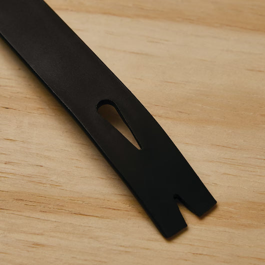 A close-up of the STANLEY 7 IN WONDER BAR® II PRY BAR, a black, precision-forged steel tool with a nail slot, resting on a light wooden surface.