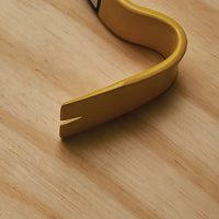 Close-up of the claw end of a yellow STANLEY® STEEL FLAT WONDER BAR® - 15IN resting on light wood. This sturdy tool from STANLEY features a flat, forked tip perfect for pulling nails or prying objects apart.