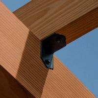 Close-up of a wooden beam joint with a Simpson Strong-Tie SIMPSON APA21 APA 90° Angle against a clear blue sky. Perfect for outdoor projects, the sunlight casts distinct shadows, highlighting the wood grain and the brackets details.