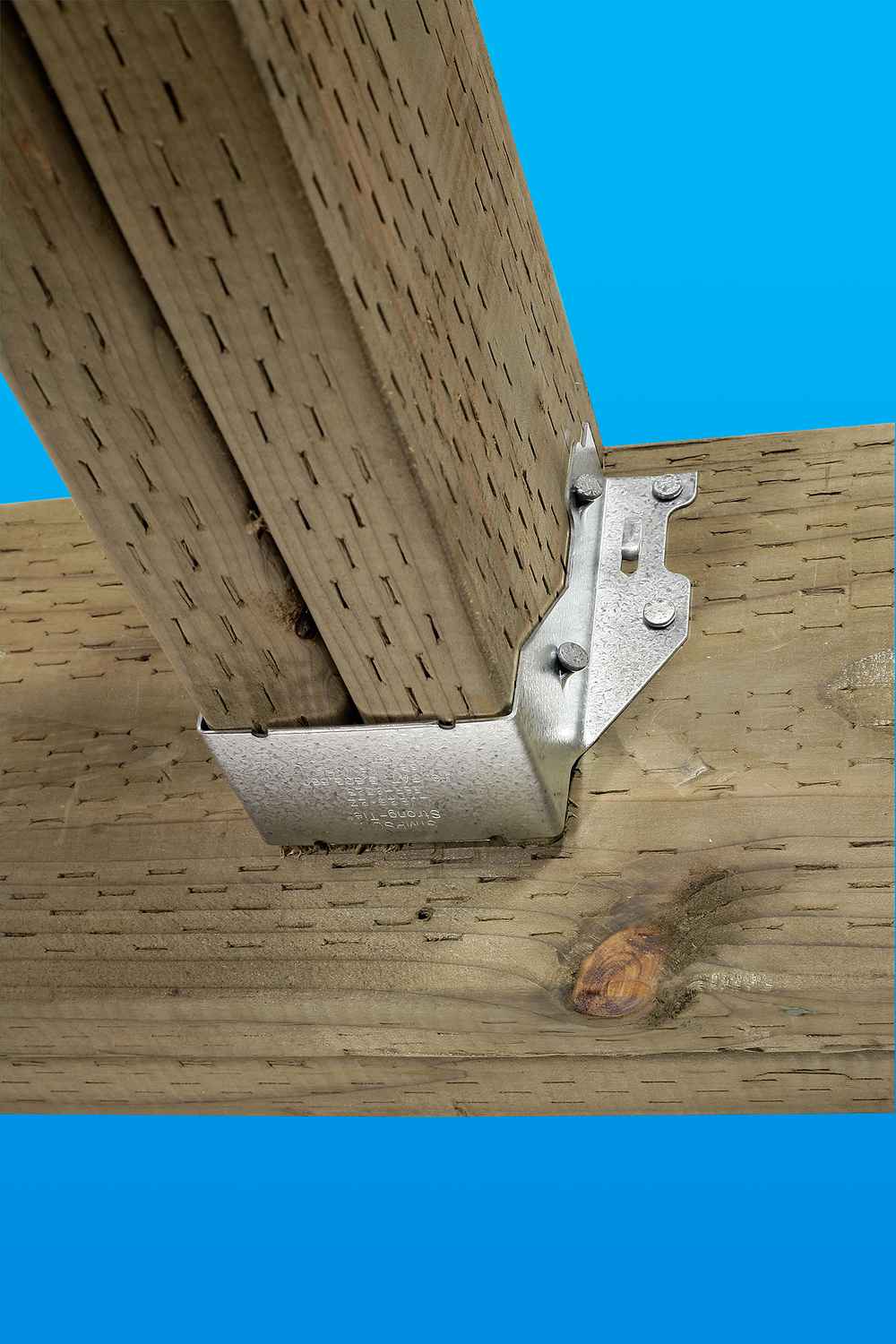 A Simpson Strong-Tie ZMAX® LUS26Z single 18-gauge face mount joist hanger secures a vertical wooden post to a horizontal beam, shown against a bright blue background.