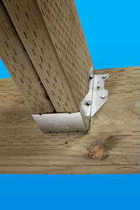 A Simpson Strong-Tie ZMAX® LUS26Z single 18-gauge face mount joist hanger secures a vertical wooden post to a horizontal beam, shown against a bright blue background.