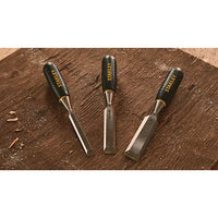 The STANLEY® WOOD CHISEL 3PC. SET (13,19,25MM) features three essential chisels on a workbench amid wood shavings—perfect tools for any craftsperson.