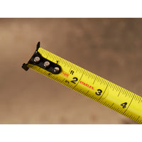 A close-up of the STANLEY 16 ft. CONTROL-LOCK™ Tape Measure, extended to show measurements from 1 to 4 inches, set against a blurred brown background.