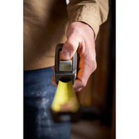 A person wearing a tan long-sleeve shirt holds and extends a STANLEY 30 ft. CONTROL-LOCK™ Tape Measure, highlighting their hand and the durable tape.