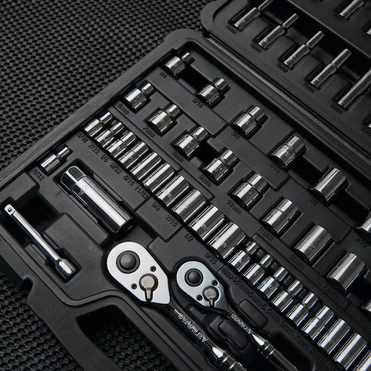 A close-up of the STANLEY 85PC SKT SET: a black plastic case with organized chrome vanadium steel socket wrenches, ratchets, and assorted sockets and bits, displayed on a textured dark surface.