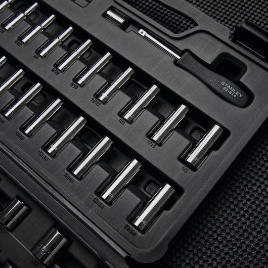 A black plastic case labeled STANLEY 85PC SKT SET holds chrome vanadium steel sockets and a ratchet handle, all neatly organized and size-labeled, resting on a textured black surface.