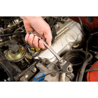 A persons hand uses a STANLEY MECHANIC TOOL SET (201 PC) wrench to tighten or loosen a bolt on a car engine, with other engine parts visible in the background.